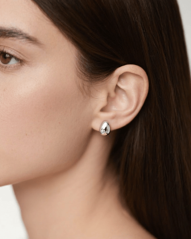 Close-up of a person wearing a silver earring with a blurred background