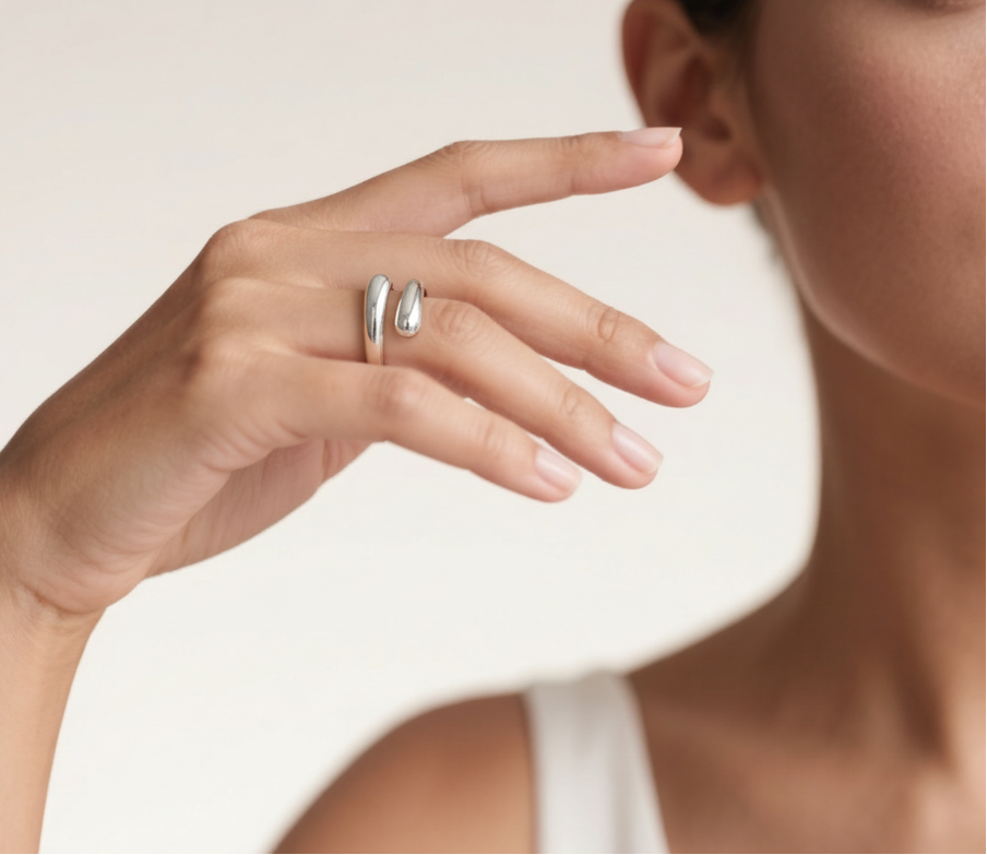 Close-up of a hand wearing two silver rings on a neutral background