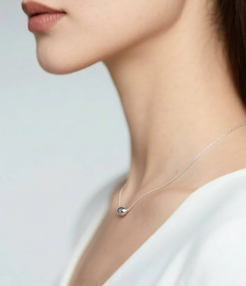 Necklace with a small pendant worn by a person against a light background