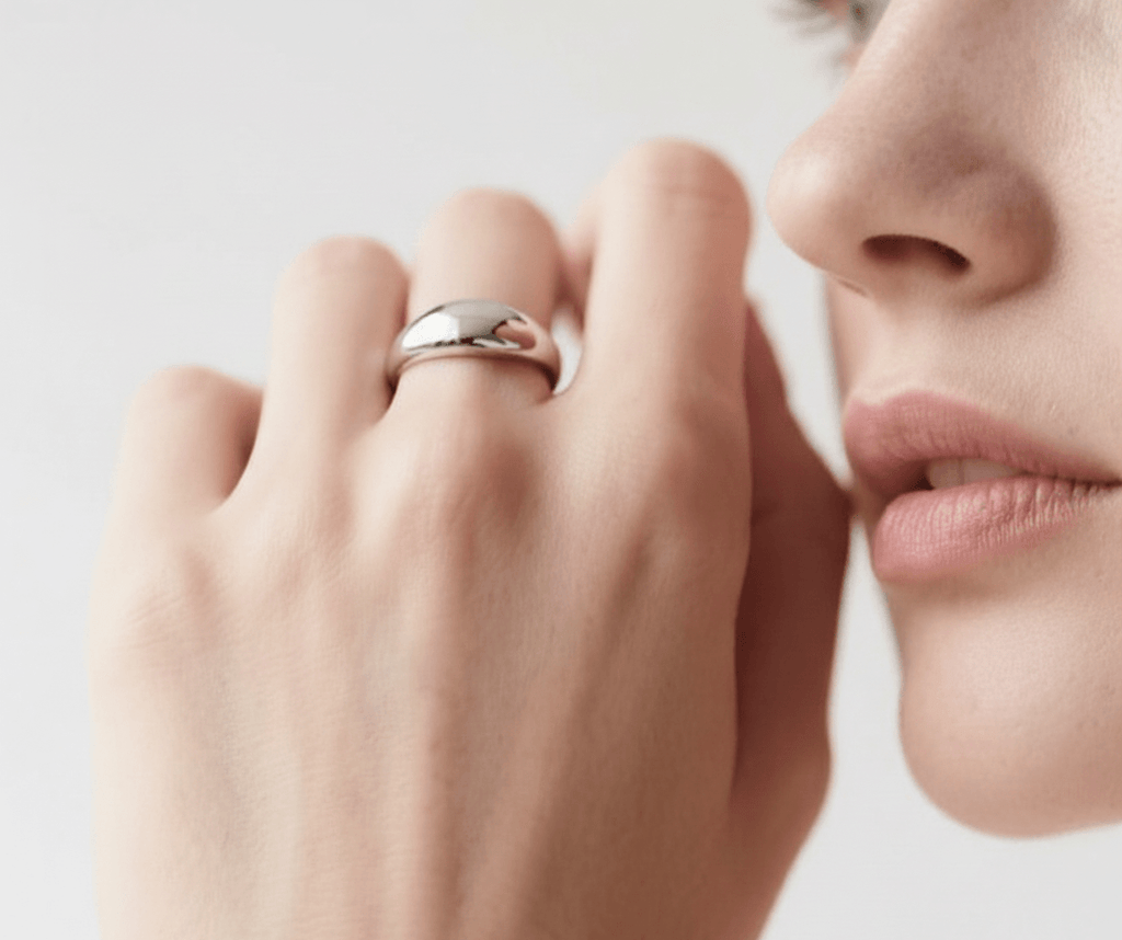 Close-up of a hand with a silver ring on a neutral background