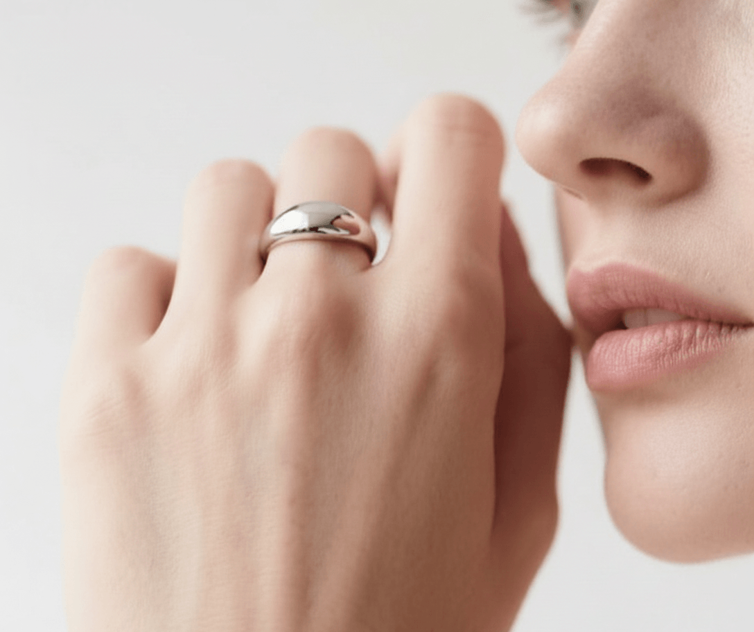 Close-up of a hand with a silver ring on a neutral background