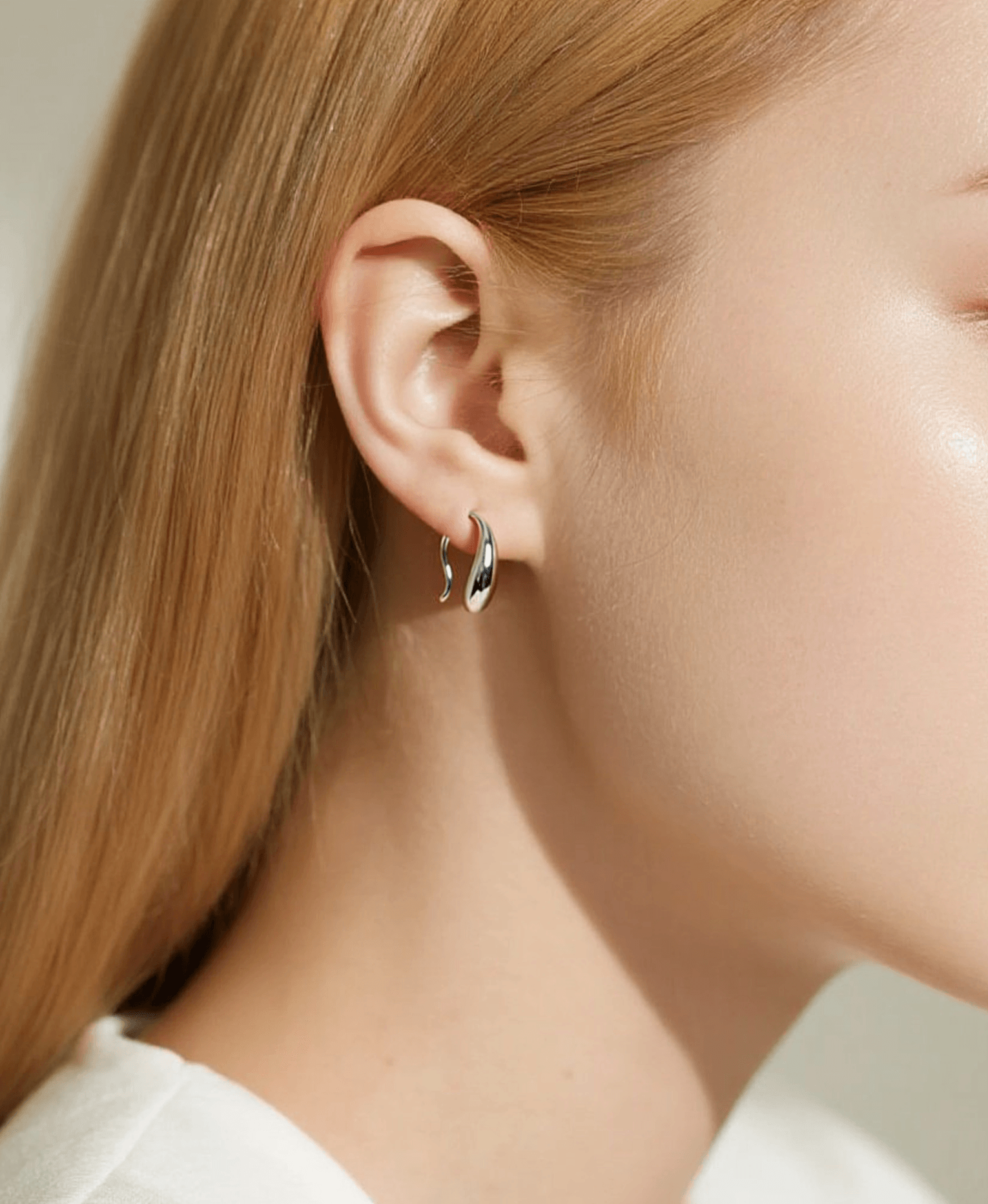 Close-up of a person wearing a silver earring with a black heart design.