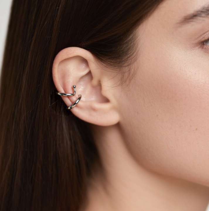 Close-up of a woman's ear wearing a silver earring with a white background