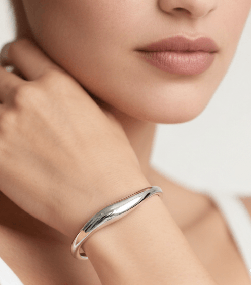 Silver bracelet on a wrist with a neutral background